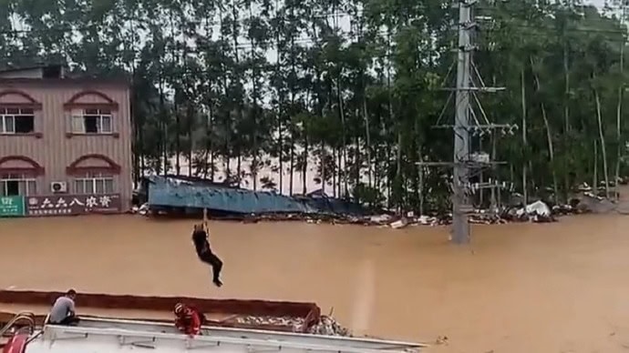 洪水救援行動 大水中有人吊著繩索被救援.